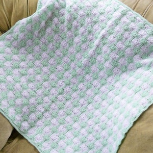 May include: A crocheted baby blanket in a green and white checkered pattern.