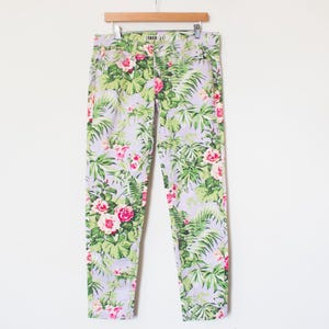May include: A pair of light purple skinny jeans with a tropical floral print featuring pink and white flowers and green leaves.