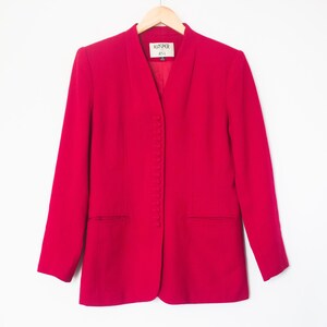 May include: A bright pink blazer with a v-neck and a button closure. The blazer has a label that reads "Woolrich 44L".