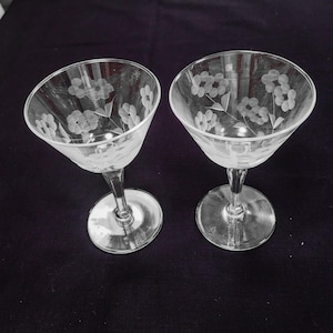 May include: Two clear glass stemmed cocktail glasses with an etched floral design.