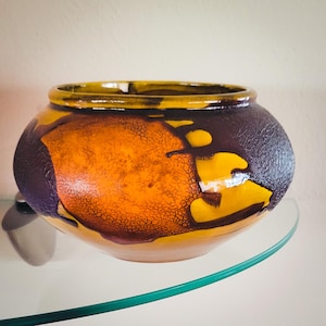 May include: A ceramic planter with a brown, orange, and yellow glaze. The glaze has a crackled effect.