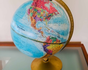 May include: A vintage blue and gold globe with a brass meridian, showing the continents of North and South America. The globe is labeled "Replogle World Station Series".