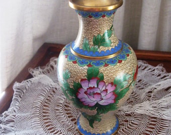 May include: A small, cream-colored porcelain vase with a gold rim and intricate floral designs in shades of blue, green, pink, and red. The vase has a classic Chinese design.