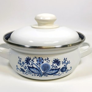 May include: White enamel pot with a lid and two handles. The pot features a blue floral design around the base and a silver rim. The lid has a white knob. A classic kitchenware item.