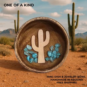 May include: A wooden ring dish and jewelry bowl with a light-colored cactus cutout and turquoise stones. The bowl is set against a desert landscape with the text "ONE OF A KIND".