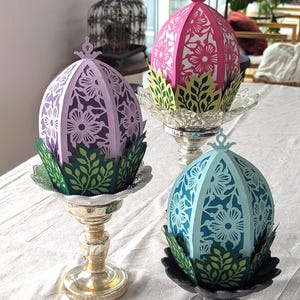 Floral Easter egg basket decor in pink, purple, and blue displayed on pedestal stands, styled as light-up spring table centerpieces for Easter and seasonal home decor.