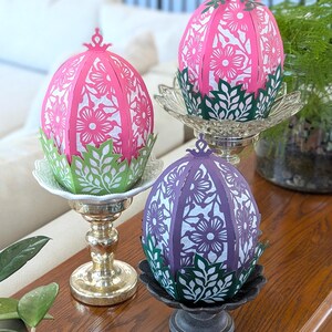 Floral Easter egg basket decor in pink and purple displayed on pedestal stands, styled on a wooden table as spring table centerpieces for Easter home decor.