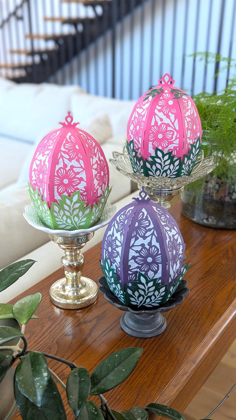 Floral Easter egg basket decor in pink and purple displayed on pedestal stands, styled on a wooden table as spring table centerpieces for Easter home decor.
