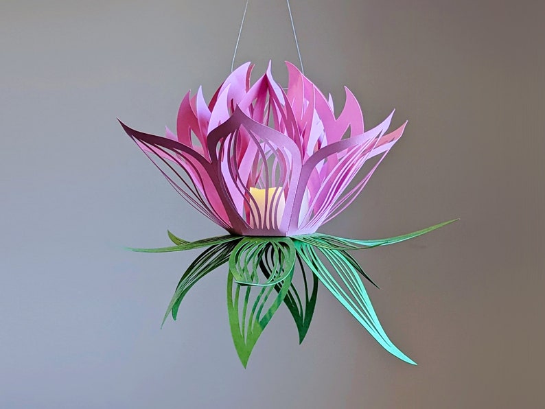 Pink and green 3D paper lotus lantern glowing with an LED tealight, crafted from a downloadable SVG file for Cricut and Silhouette machines.
