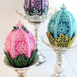 Floral Easter egg basket decor in pink, blue, and purple displayed on pedestal stands, styled as spring table centerpieces and decorative Easter home accents.