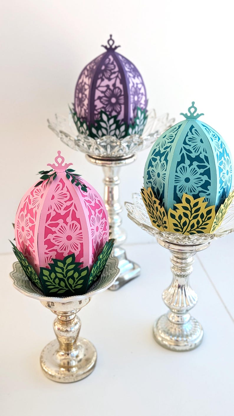 Floral Easter egg basket decor in pink, blue, and purple displayed on pedestal stands, styled as spring table centerpieces and decorative Easter home accents.