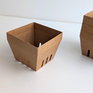 A plain kraft cardstock berry basket bases without lace edges, shown empty on a white background, demonstrating the base structure for the Lace Berry Basket SVG treat holder template for Cricut and cutting machines.
