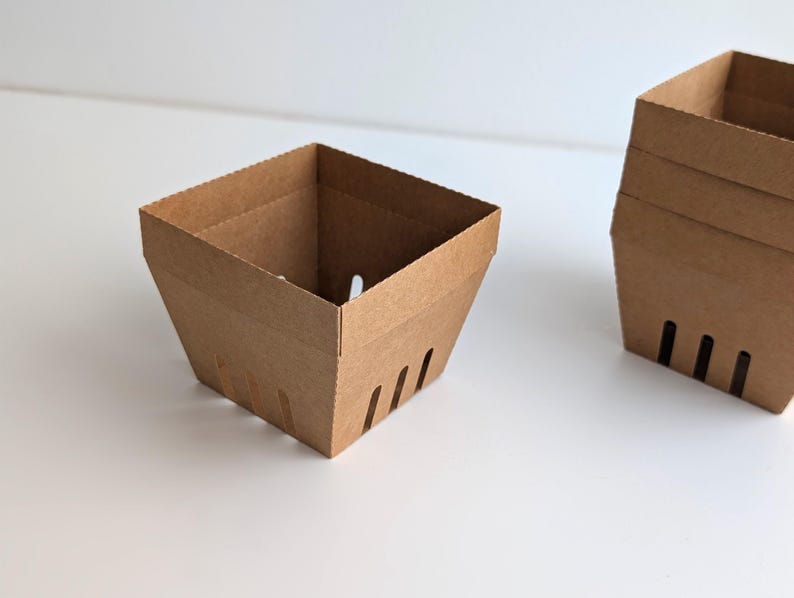 A plain kraft cardstock berry basket bases without lace edges, shown empty on a white background, demonstrating the base structure for the Lace Berry Basket SVG treat holder template for Cricut and cutting machines.