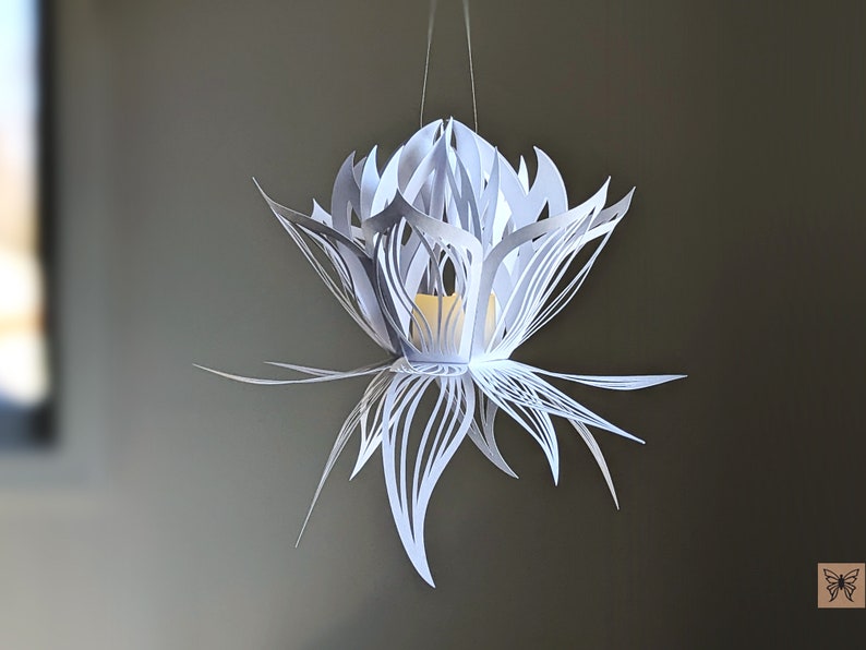 Single white 3D paper lotus lantern hanging from a string with a flickering LED tealight inside, crafted using a lotus lantern SVG for Cricut and Silhouette.
