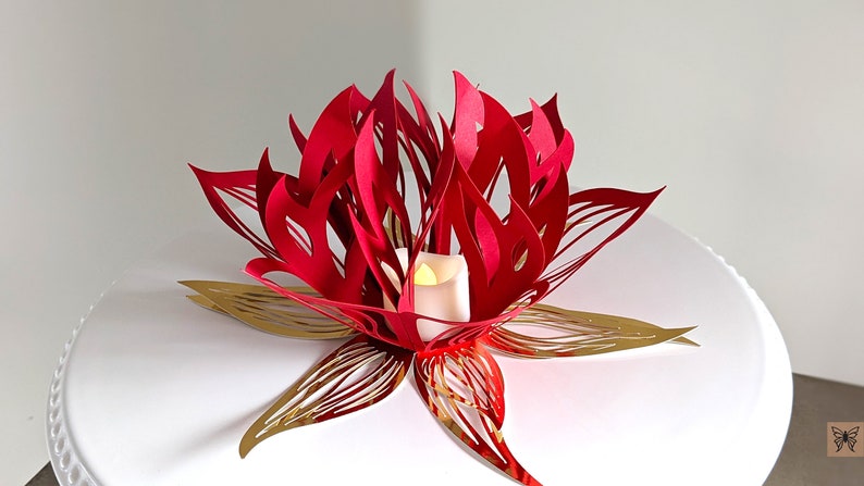 Red and gold 3D paper lotus centerpiece with a glowing LED tealight, made from a lotus lantern SVG for Cricut and Silhouette.