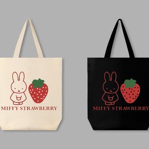 May include: Two tote bags, one cream and one black, each featuring a red outline illustration of a bunny and a strawberry. The text "MIFFY STRAWBERRY" is printed below the images. The bags have long handles.