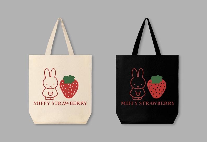 May include: Two tote bags, one cream and one black, each featuring a red outline illustration of a bunny and a strawberry. The text "MIFFY STRAWBERRY" is printed below the images. The bags have long handles.
