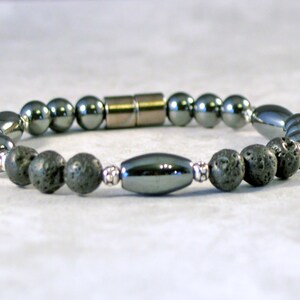 Puede incluir: Un brazalete negro y plateado con cuentas redondas y un cierre magnético.