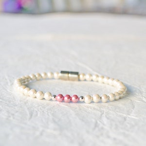 Magnetic bracelet handcrafted w/ cream pearl hematite magnetic beads w/ pink pearl hematite magnetic beads in the center. Two sterling silver beads surround the pink magnetic beads in the center. The bracelet is secured with a strong magnetic clasp.