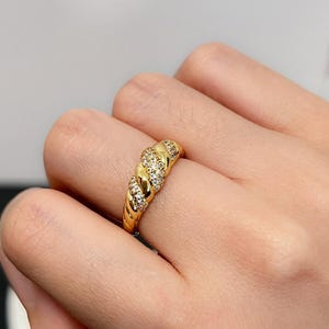 Peut inclure: Une bague en or avec une bande torsadée et de petites pierres claires serties dans la bande.
