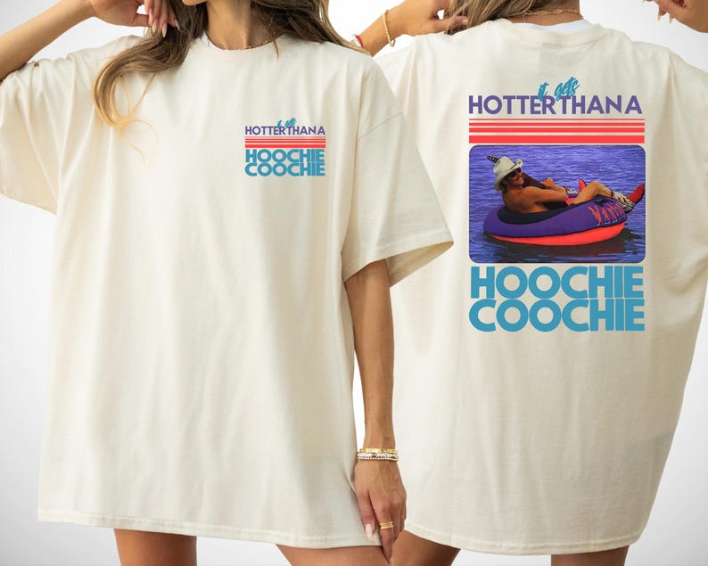 May include: An off-white t-shirt featuring a small graphic on the front and a large graphic on the back. The text reads IT GETS HOTTER THAN A HOOCHIE COOCHIE. The back graphic shows a person in a hat floating on a purple and red inner tube.