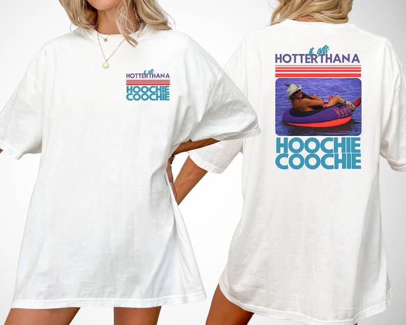 May include: A white t-shirt featuring a graphic on the front left chest and a larger version on the back. The design includes red horizontal stripes, the text "HOTTERTHANA" and "HOOCHIE COOCHIE" in blue, and a photo of a person in a tube.