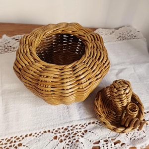 May include: A round, golden-brown woven basket with a pumpkin-like shape and a matching lid. The basket features a textured, coiled weave pattern with a scalloped rim. The separate lid includes a small, central woven handle for easy removal.