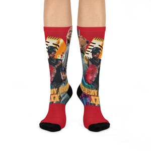 Peut inclure: Chaussettes rouges avec un collage d'images de musiciens et un motif de microphone doré. Les chaussettes ont des talons et des orteils noirs, et le mot "WAY" est visible sur le devant.