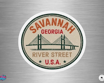 May include: A round sticker featuring a vintage design with the words "Savannah Georgia River Street U.S.A." in a circular layout. The design includes a bridge illustration in green and a beige background.