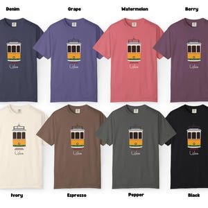 K&ouml;nnte beinhalten: Eine Kollektion von acht kurz&auml;rmeligen T-Shirts in verschiedenen Farben, jeweils mit einer gelb-wei&szlig;en Stra&szlig;enbahn-Illustration und dem Wort "Lisbon" darunter. Farben: Denim, Traube, Wassermelone, Beere, Elfenbein, Espresso, Pfeffer und Schwarz.