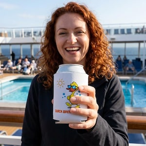 K&ouml;nnte beinhalten: Ein wei&szlig;er Getr&auml;nkedosenk&uuml;hler mit einer Cartoon-Ente mit Sonnenbrille, einer Sonne und dem Text "QUACK OPEN". Der Getr&auml;nkedosenk&uuml;hler wird von einer Person mit roten Haaren in der N&auml;he eines Swimmingpools gehalten.