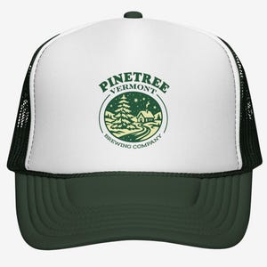 May include: A green and white trucker cap with a curved peak. The front panel features a circular logo with the text "Pinetree Vermont Brewing Company" around an illustration of a house, trees, and a road.