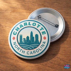 Pu&ograve; includere: Un bottone rotondo con un design turchese e bianco raffigurante lo skyline di Charlotte, Carolina del Nord. Il testo "CHARLOTTE NORTH CAROLINA" &egrave; stampato sul bordo. &Egrave; visibile un secondo bottone con spilla.
