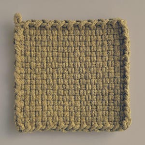 May include: A square, woven potholder in a light tan colour. The potholder has a looped corner for hanging and a braided edge. The weave pattern is tight and uniform, creating a textured surface. This kitchen item is designed for heat resistance.