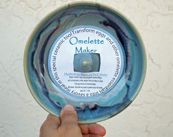 May include: A blue and green ceramic omelette maker with the text "Transform eggs and other omelette essentials into a savory meal in this special ceramic tool Omelette Maker" and "Handmade by Alyssa at Clay Eclectics".
