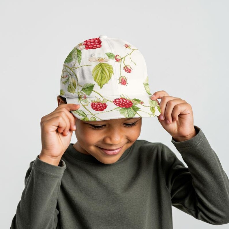 May include: A white baseball cap featuring a vibrant raspberry and leaf pattern. The cap has a curved brim and a classic six-panel design. The design includes red raspberries, green leaves, and white flowers.