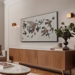 May include: A modern living room featuring a large wooden cabinet with a marble top, a round coffee table, and a framed artwork depicting flying birds. The artwork is the focal point, with a neutral color palette.
