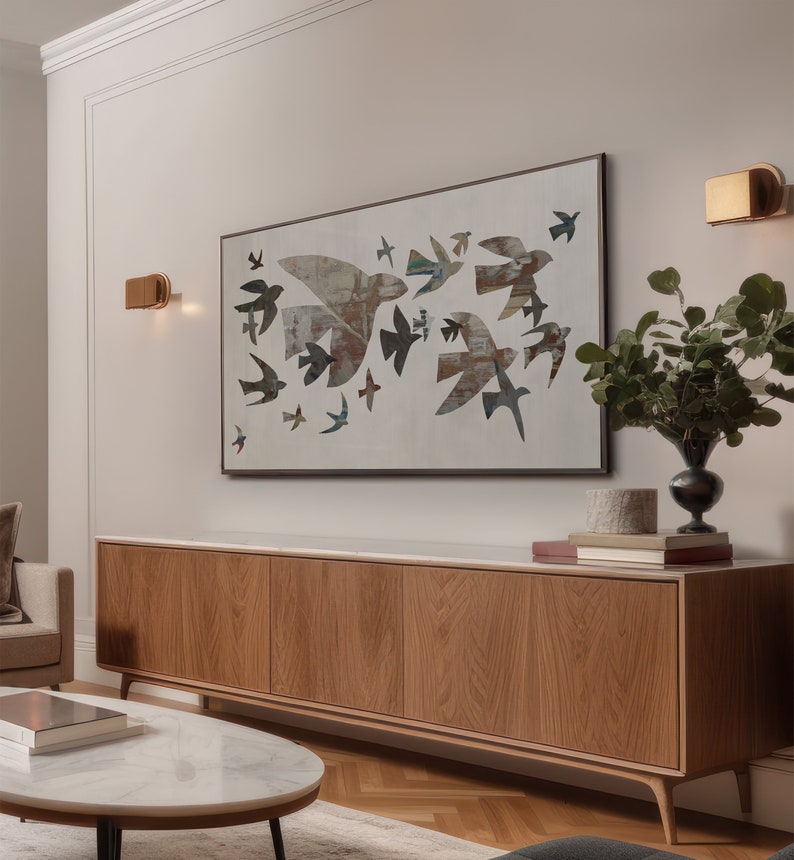 May include: A modern living room featuring a large wooden cabinet with a marble top, a round coffee table, and a framed artwork depicting flying birds. The artwork is the focal point, with a neutral color palette.