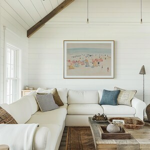 May include: A white sectional sofa with throw pillows and a white throw blanket sits in front of a white shiplap wall with a framed watercolor painting of a beach scene. A wooden coffee table with a woven basket and a decorative stone sits in front of the sofa. A brown patterned rug is on the floor.