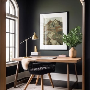 Puede incluir: Una oficina en casa con una pared verde oscuro, un escritorio de madera con una silla negra tejida, una l&aacute;mpara dorada y una pintura de paisaje enmarcada. Un jarr&oacute;n con hojas verdes se encuentra en el escritorio.