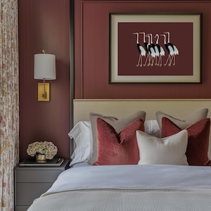 May include: A bedroom with a burgundy wall, a white bed with a beige headboard, and a framed print of black and white birds on a burgundy background.