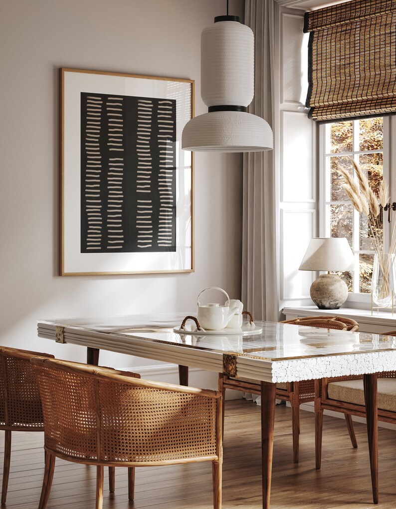 May include: A dining room with a white table with a white and gold inlay design. The table has a glass top and is surrounded by four wicker chairs. A white pendant light hangs above the table. A black and white abstract print hangs on the wall behind the table.