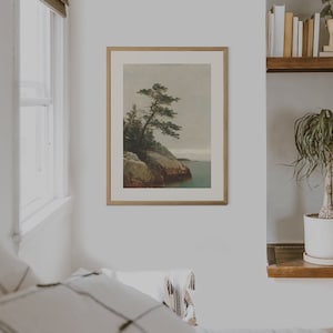 May include: A framed print of a painting depicting a lone pine tree growing on a rocky cliff overlooking a body of water. The sky is a muted gray, and the water is a deep blue.