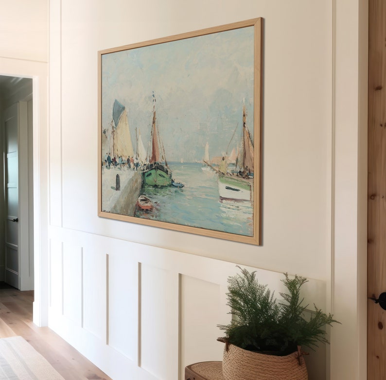 K&ouml;nnte beinhalten: Ein gerahmtes Gem&auml;lde, das eine Meereslandschaft mit mehreren Segelbooten zeigt, die an einem Pier festgemacht sind. Das Gem&auml;lde ist in einem hellen Holzrahmen gefasst und h&auml;ngt an einer wei&szlig;en Wand.