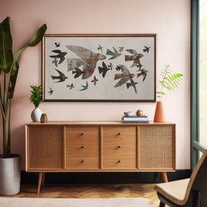 May include: A mid-century modern style wooden sideboard with three drawers and two woven cane door panels. Above the sideboard is a framed artwork featuring a flock of stylized birds in flight, in shades of brown, gray, and blue. A tall potted plant and vase are on either side.