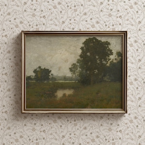 Puede incluir: Una pintura de paisaje enmarcada que representa una escena rural con un gran árbol en primer plano y una vista lejana de un lago. La pintura está sobre un fondo de cielo gris claro con toques de nubes.