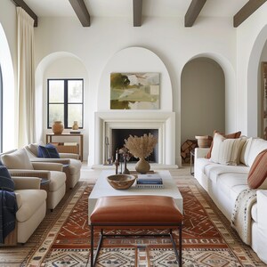 May include: A living room with a white sofa, two armchairs, a coffee table, and a fireplace. The room has a white and brown color scheme and features a large rug with a geometric pattern.