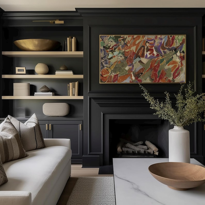 May include: A living room featuring a black cabinet and fireplace. The shelves display decorative items, including a gold bowl and books. A white sofa with patterned cushions sits in front of the cabinet. An abstract painting hangs above the fireplace.