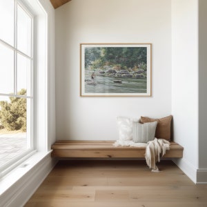 May include: A wooden bench with two pillows and a throw blanket sits in a corner of a room with a large window and a framed watercolor painting of a river scene.