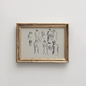 Op de afbeelding: Een ingelijst kunstwerk met een schets van verschillende figuren in donkergrijs op een lichtgrijze achtergrond. Het kunstwerk bevindt zich in een goudkleurige lijst. De figuren zijn afgebeeld met eenvoudige lijnen, wat een menigte of bijeenkomst suggereert.